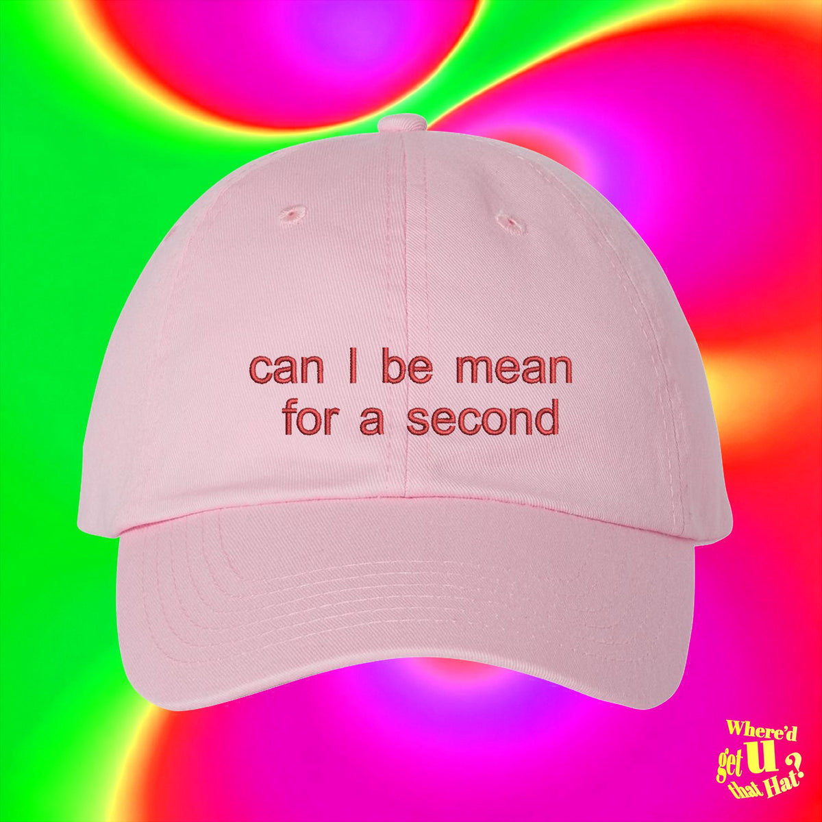 A pink baseball cap with the text "can I be mean for a second" printed on it, against a colorful, gradient background.
